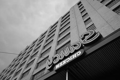 high rise Saucy Chicken signage on building greyscale photo town